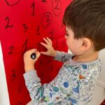 Copii încercuiesc cifra corectă pe planșă în cadrul unei activități matematice la grădiniță