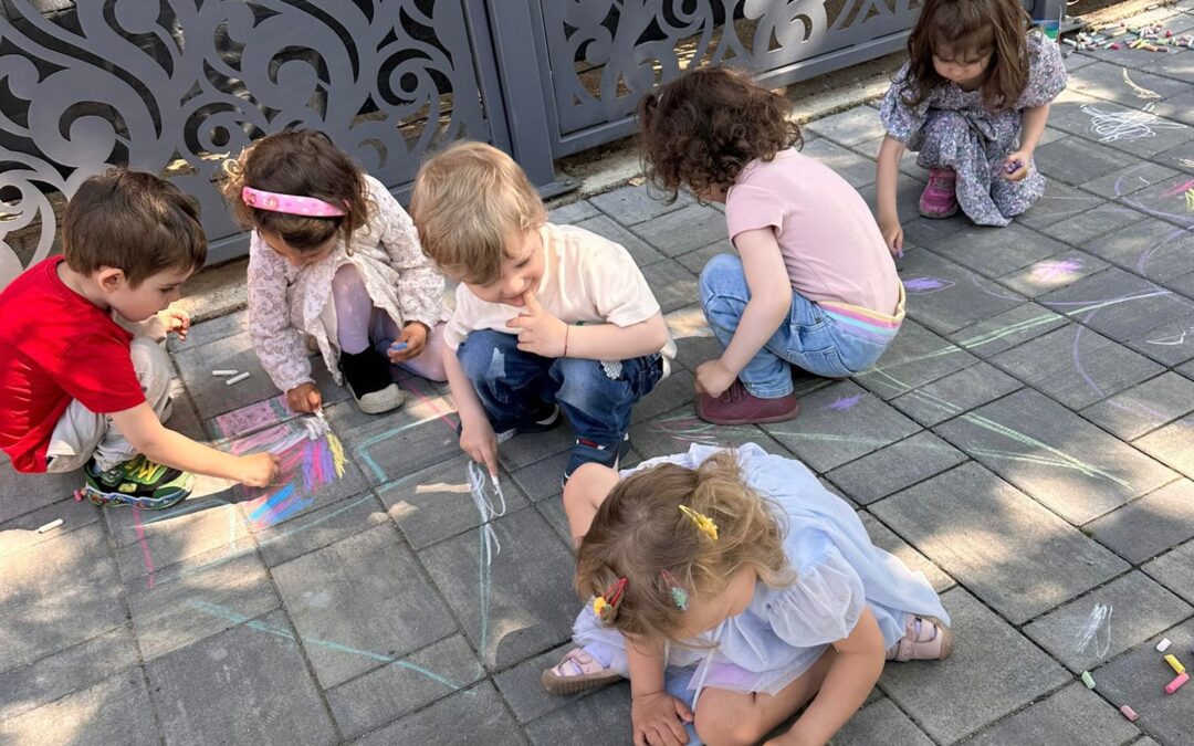 Copii de la Grădinița Don Castor din Sector 2 București participă la activitatea de desene pe asfalt cu cretă colorată de Ziua Copiilor.