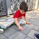 Copii fericiți participă la activitatea Desene pe asfalt organizată de Grădinița Don Castor din Sector 2 București.